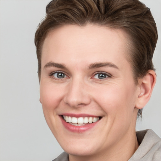 Joyful white young-adult female with short  brown hair and grey eyes