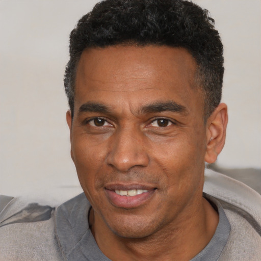 Joyful black adult male with short  black hair and brown eyes
