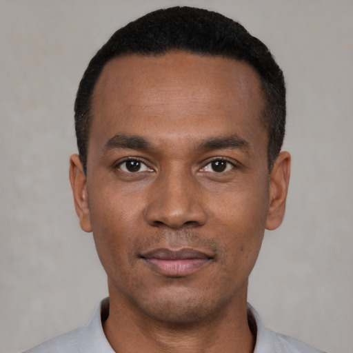 Joyful black young-adult male with short  black hair and brown eyes