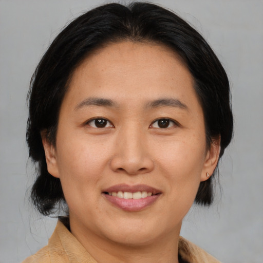 Joyful asian adult female with medium  brown hair and brown eyes