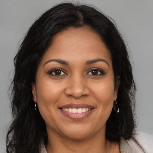 Joyful black adult female with long  brown hair and brown eyes