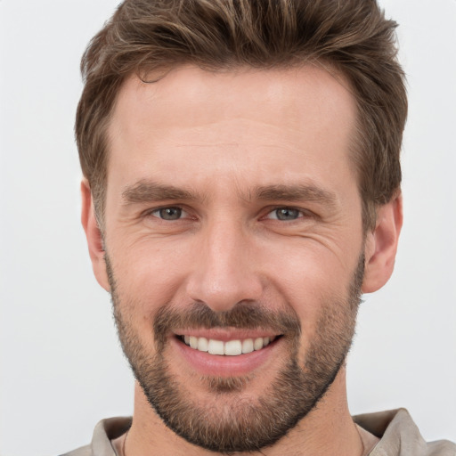 Joyful white young-adult male with short  brown hair and grey eyes