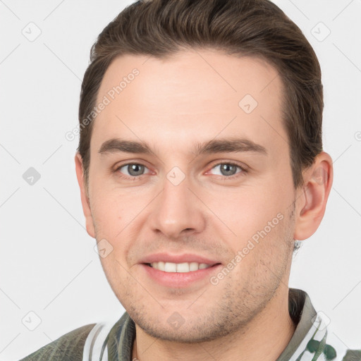 Joyful white young-adult male with short  brown hair and grey eyes