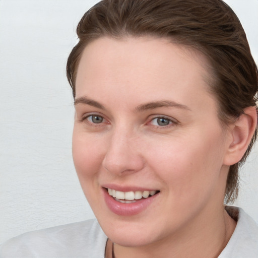 Joyful white young-adult female with short  brown hair and blue eyes