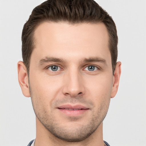 Joyful white young-adult male with short  brown hair and grey eyes