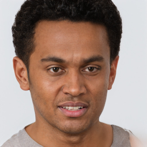 Joyful black young-adult male with short  brown hair and brown eyes