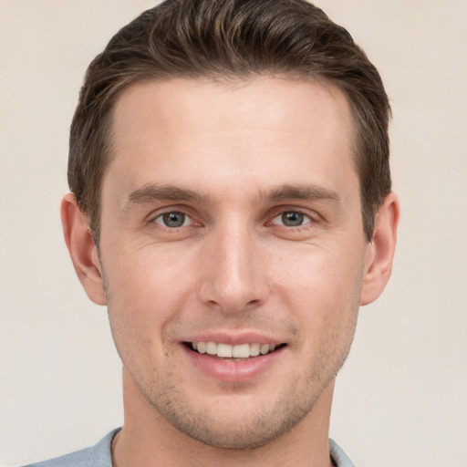 Joyful white young-adult male with short  brown hair and grey eyes