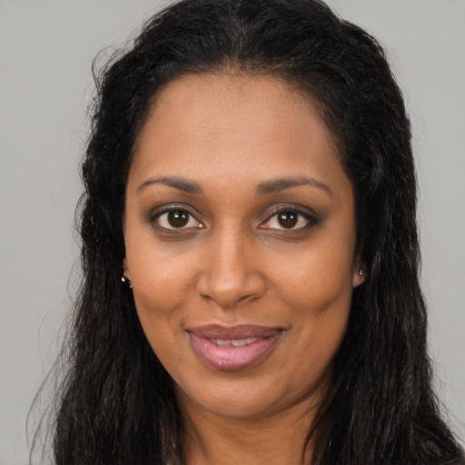 Joyful black young-adult female with long  brown hair and brown eyes