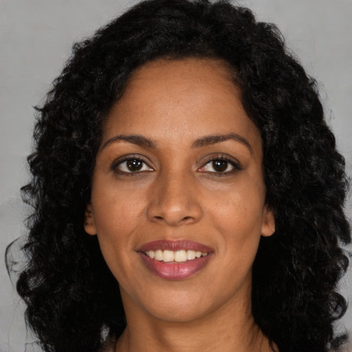 Joyful black young-adult female with long  black hair and brown eyes