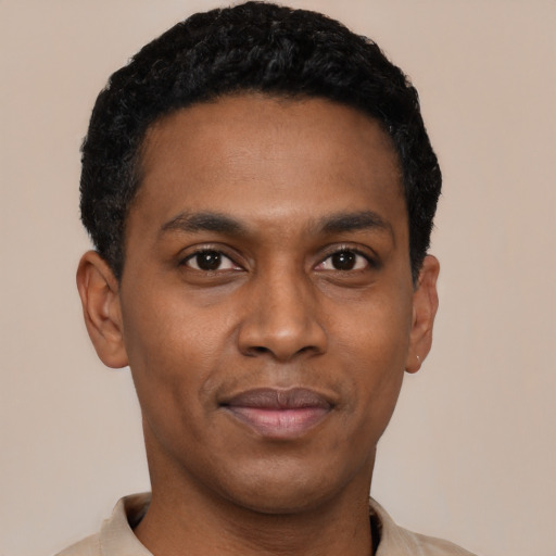 Joyful black young-adult male with short  black hair and brown eyes