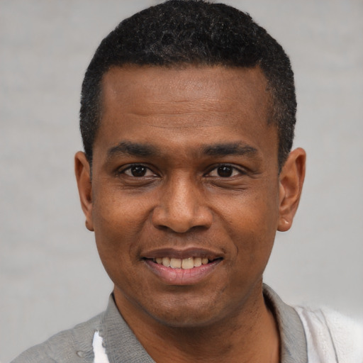 Joyful black young-adult male with short  black hair and brown eyes