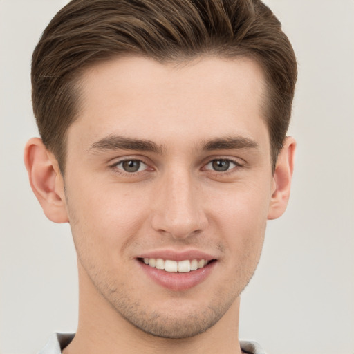 Joyful white young-adult male with short  brown hair and grey eyes