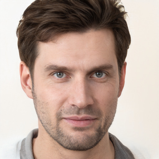 Joyful white young-adult male with short  brown hair and grey eyes