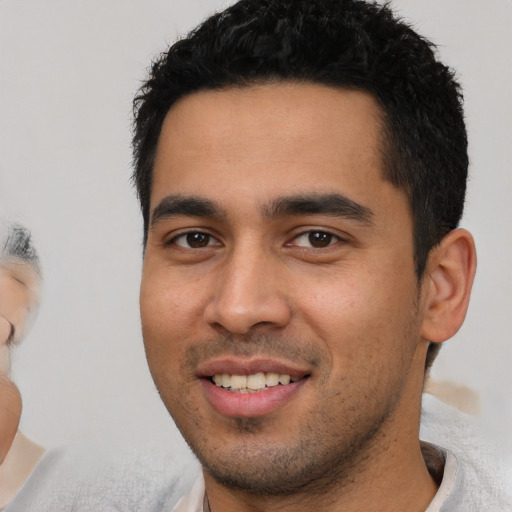 Joyful latino young-adult male with short  black hair and brown eyes