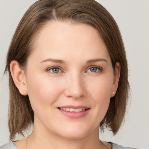 Joyful white young-adult female with medium  brown hair and grey eyes