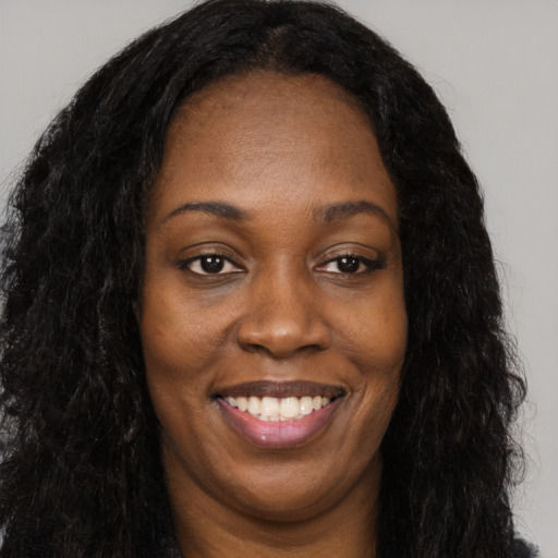 Joyful black young-adult female with long  black hair and brown eyes