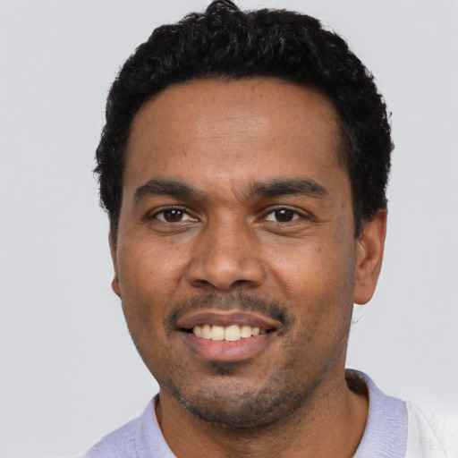 Joyful black young-adult male with short  black hair and brown eyes