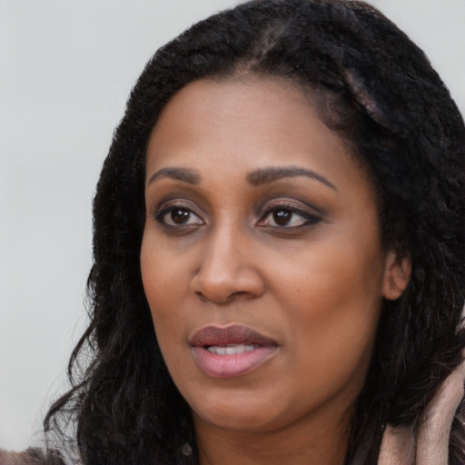 Joyful black young-adult female with long  black hair and brown eyes