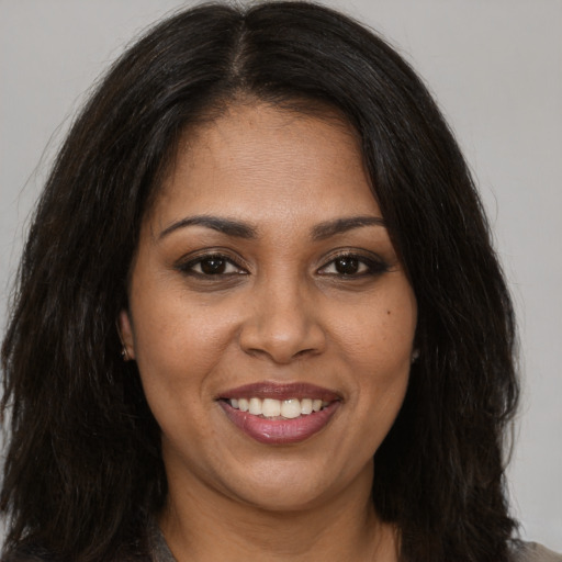 Joyful black young-adult female with long  brown hair and brown eyes