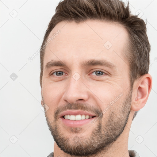 Joyful white young-adult male with short  brown hair and grey eyes