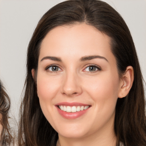 Joyful white young-adult female with long  brown hair and brown eyes