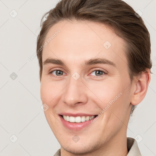 Joyful white young-adult male with short  brown hair and grey eyes