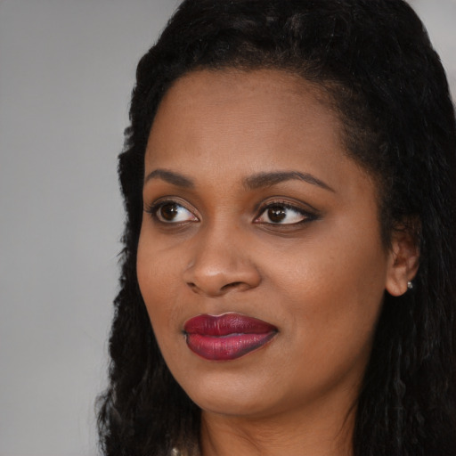 Joyful black young-adult female with long  black hair and brown eyes