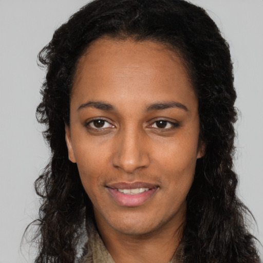 Joyful black young-adult female with long  brown hair and brown eyes