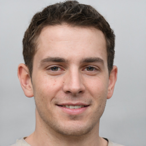 Joyful white young-adult male with short  brown hair and grey eyes