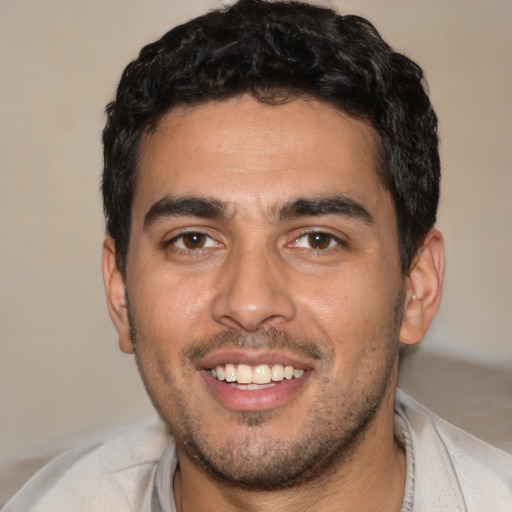 Joyful latino young-adult male with short  brown hair and brown eyes