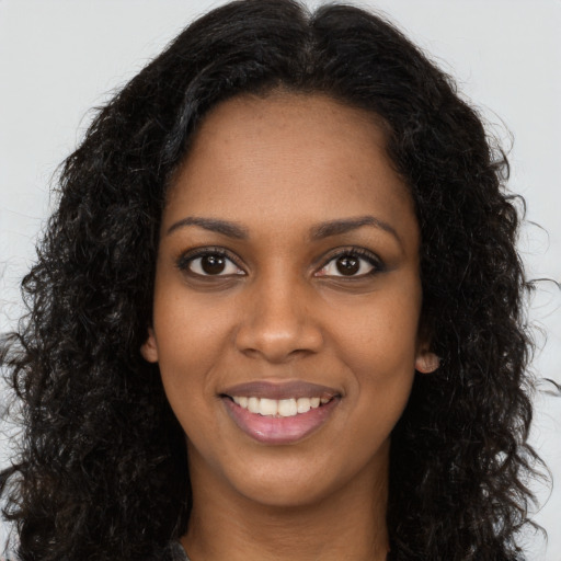 Joyful black young-adult female with long  brown hair and brown eyes