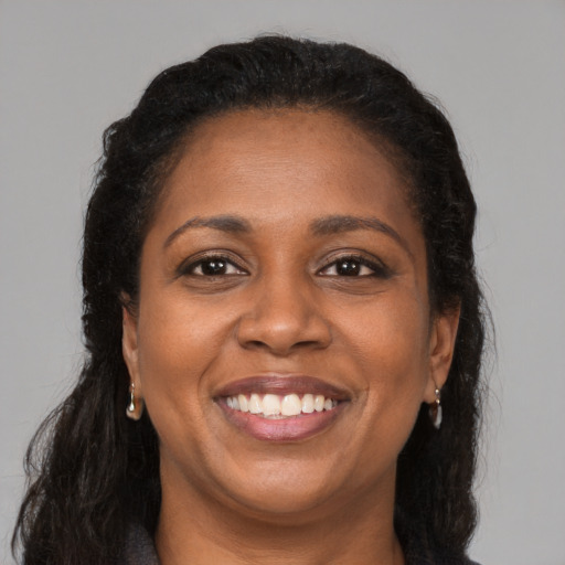 Joyful black young-adult female with long  brown hair and brown eyes