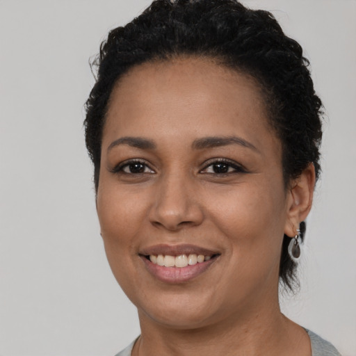 Joyful black young-adult female with short  black hair and brown eyes
