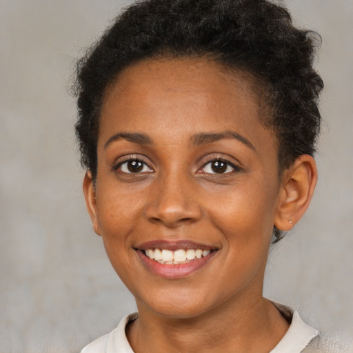 Joyful black young-adult female with short  brown hair and brown eyes