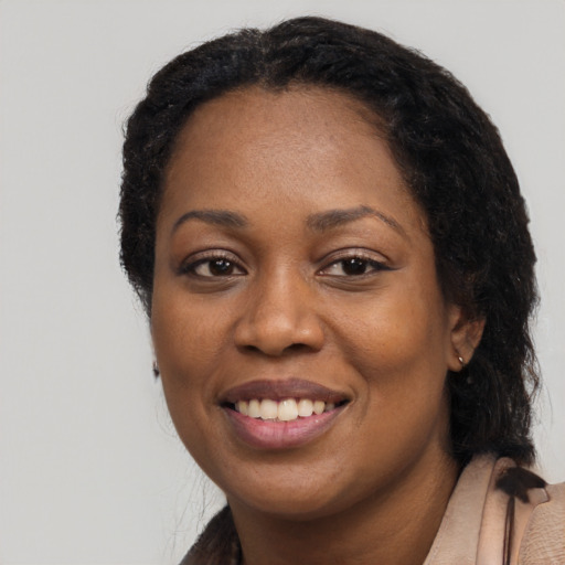 Joyful black young-adult female with long  black hair and brown eyes