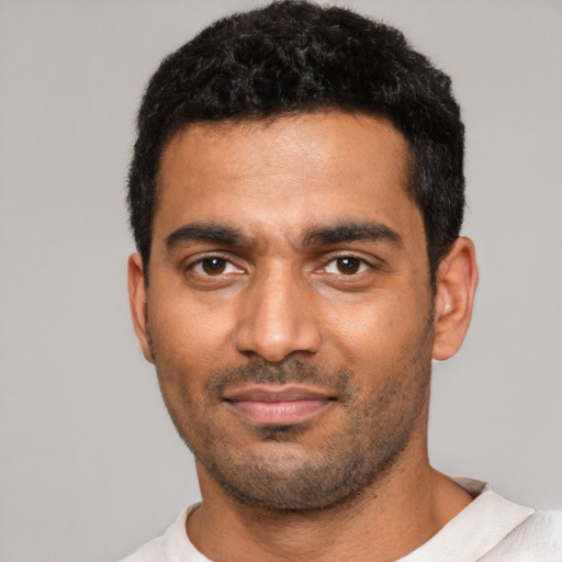 Joyful black young-adult male with short  black hair and brown eyes