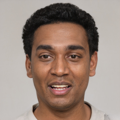 Joyful black young-adult male with short  black hair and brown eyes