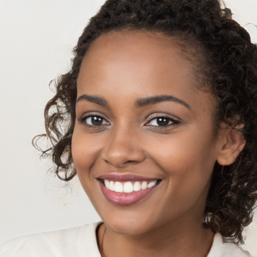 Joyful black young-adult female with long  brown hair and brown eyes