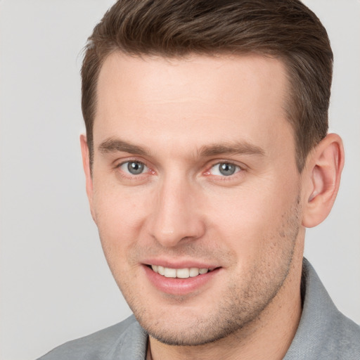 Joyful white young-adult male with short  brown hair and grey eyes