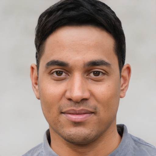 Joyful latino young-adult male with short  black hair and brown eyes
