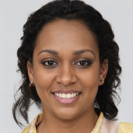 Joyful black young-adult female with long  brown hair and brown eyes