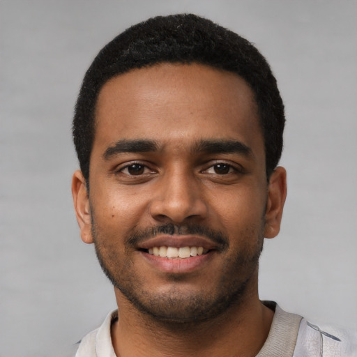 Joyful black young-adult male with short  black hair and brown eyes