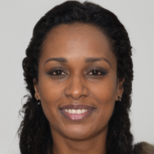 Joyful black young-adult female with long  black hair and brown eyes