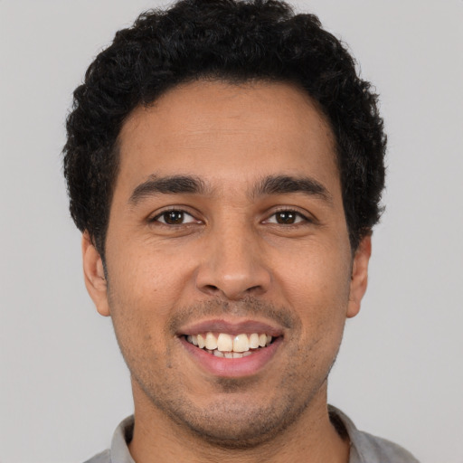 Joyful latino young-adult male with short  brown hair and brown eyes