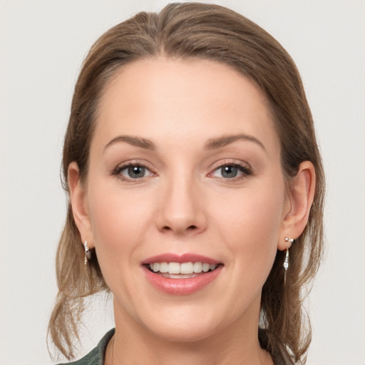 Joyful white young-adult female with medium  brown hair and grey eyes