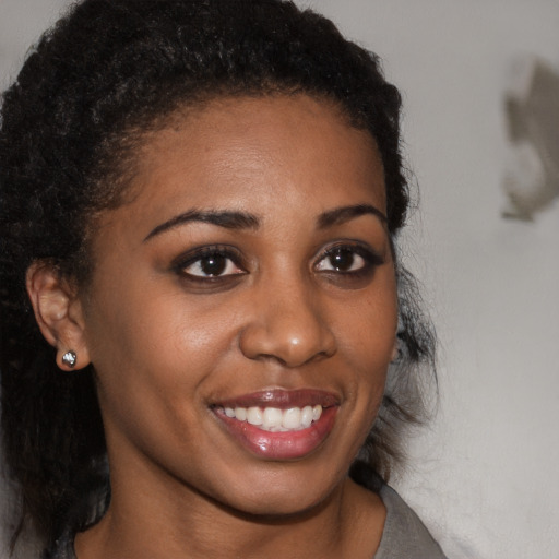 Joyful black young-adult female with long  brown hair and brown eyes