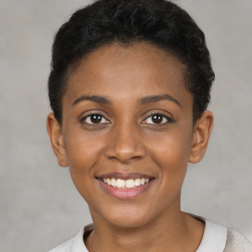 Joyful black young-adult female with short  black hair and brown eyes