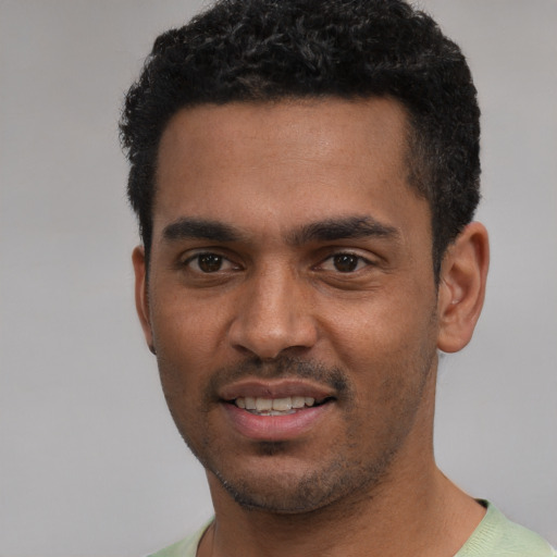 Joyful black young-adult male with short  black hair and brown eyes