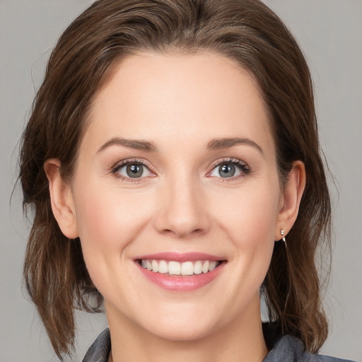 Joyful white young-adult female with medium  brown hair and grey eyes