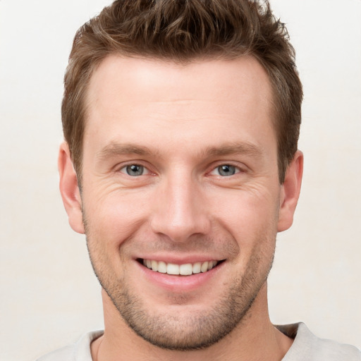 Joyful white young-adult male with short  brown hair and grey eyes